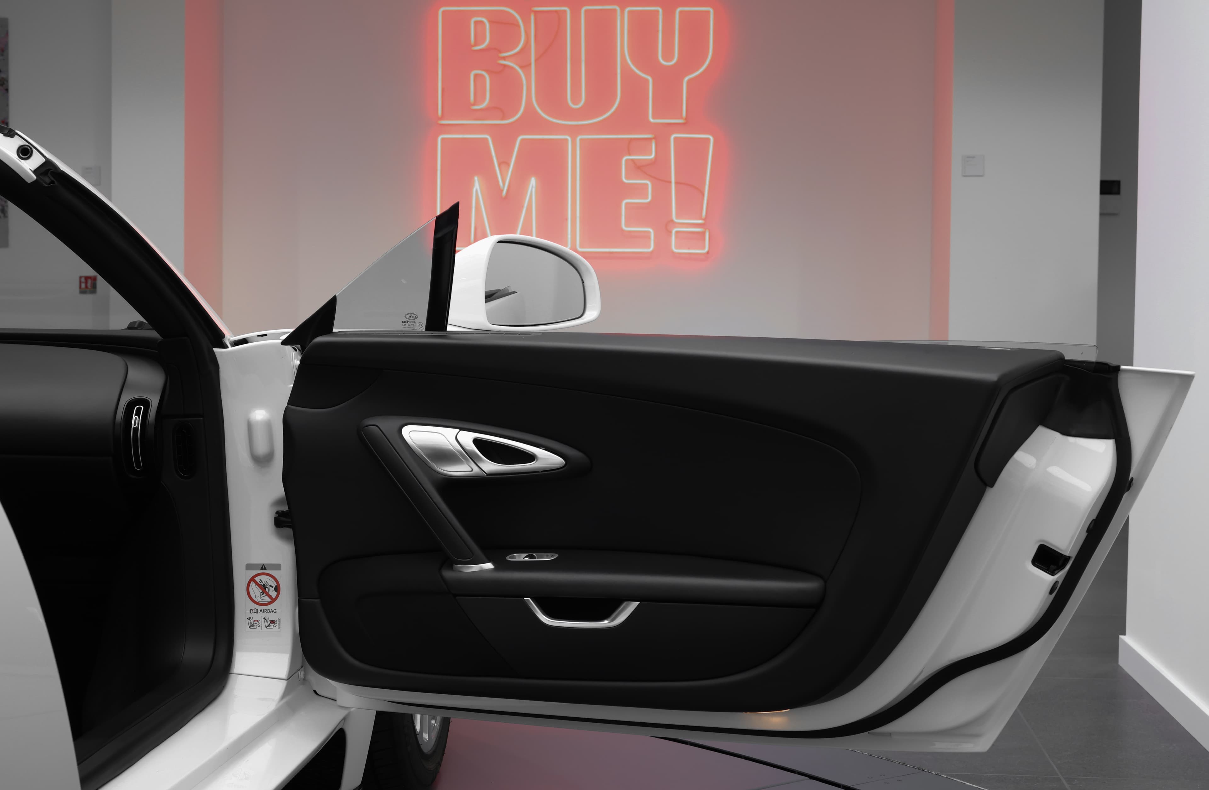 Avec la porte ouverte, l'intérieur de la Bugatti Veyron se révèle dans toute sa splendeur, offrant un accès à un habitacle somptueux où le cuir fin et les détails méticuleux se marient pour créer une atmosphère de luxe et d'exclusivité.