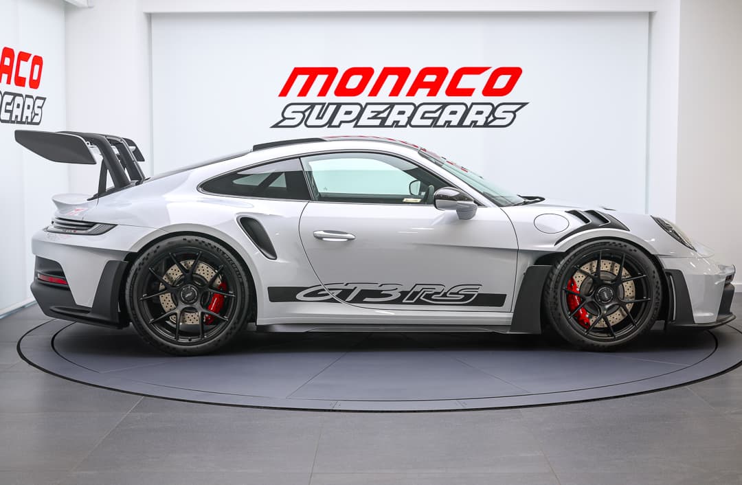 Cette vue de profil de la Porsche 911 GT3 RS met en exergue son profil élancé et ses courbes fluides, soulignant son aérodynamisme et sa silhouette emblématique qui évoquent la vitesse et la performance sur route.