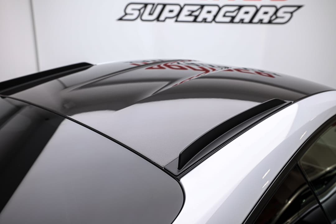 Cette vue du toit en carbone de la Porsche 911 GT3 RS souligne l'engagement de la marque envers la légèreté et la performance, avec une finition qui non seulement améliore l'esthétique sportive, mais contribue également à abaisser le centre de gravité pour une meilleure maniabilité.