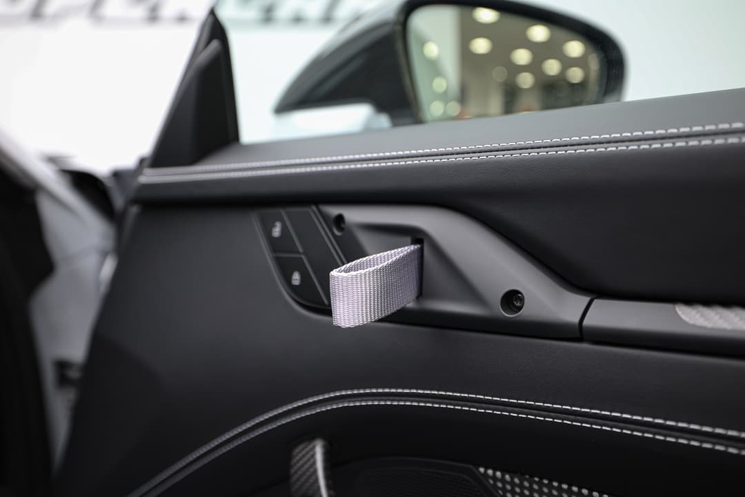 Cette image du poignet en nylon à l'intérieur de la Porsche 911 GT3 RS met en avant une solution à la fois légère et résistante, conçue pour faciliter l'accès et la manipulation des éléments de contrôle tout en ajoutant une touche de style sportif à l'habitacle.