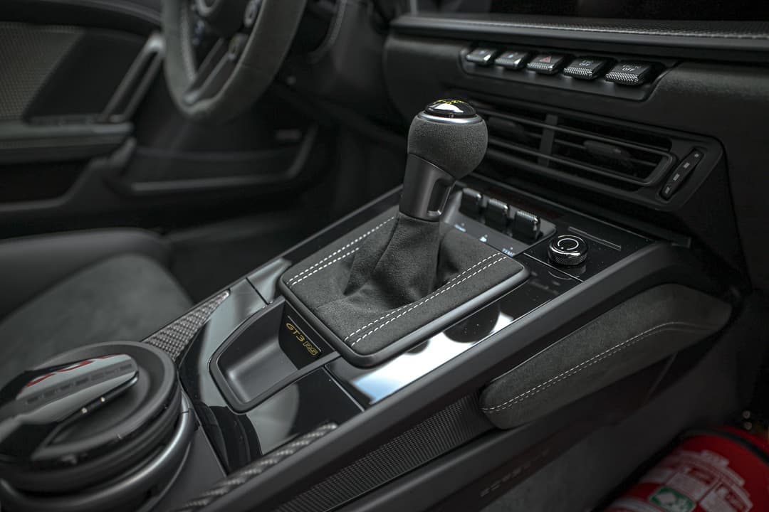 Cette image de la console centrale de la Porsche 911 GT3 RS met en avant une disposition ergonomique, avec des commandes sportives, des finitions en carbone et une technologie de pointe, créant un espace fonctionnel et stylé qui place le conducteur au cœur de l'expérience de conduite.