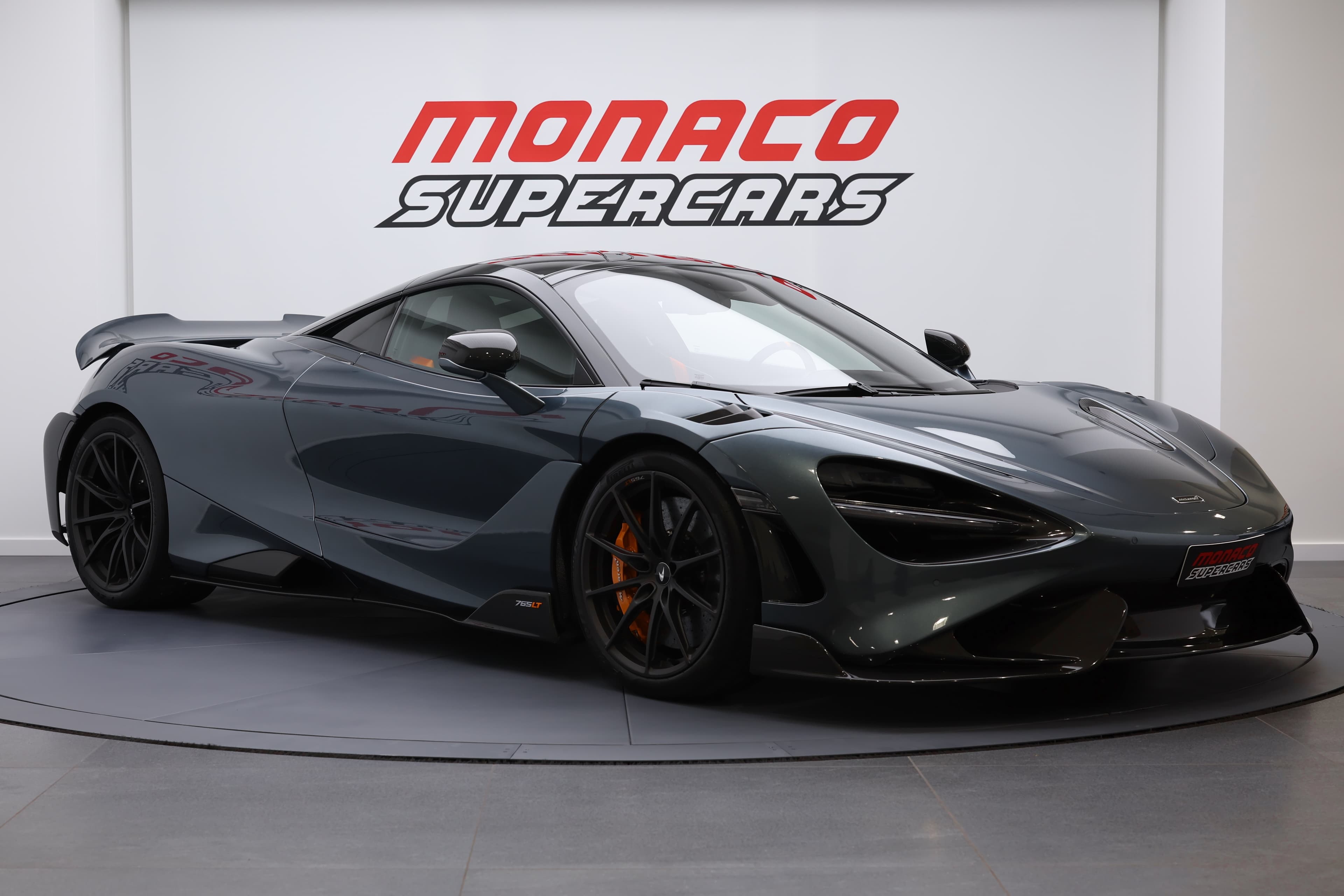 L'image montre une McLaren 765LT en vue 3/4 avant, mettant en avant son design sculpté, ses phares emblématiques et son capot aérodynamique, soulignant son caractère sportif et sa puissance.