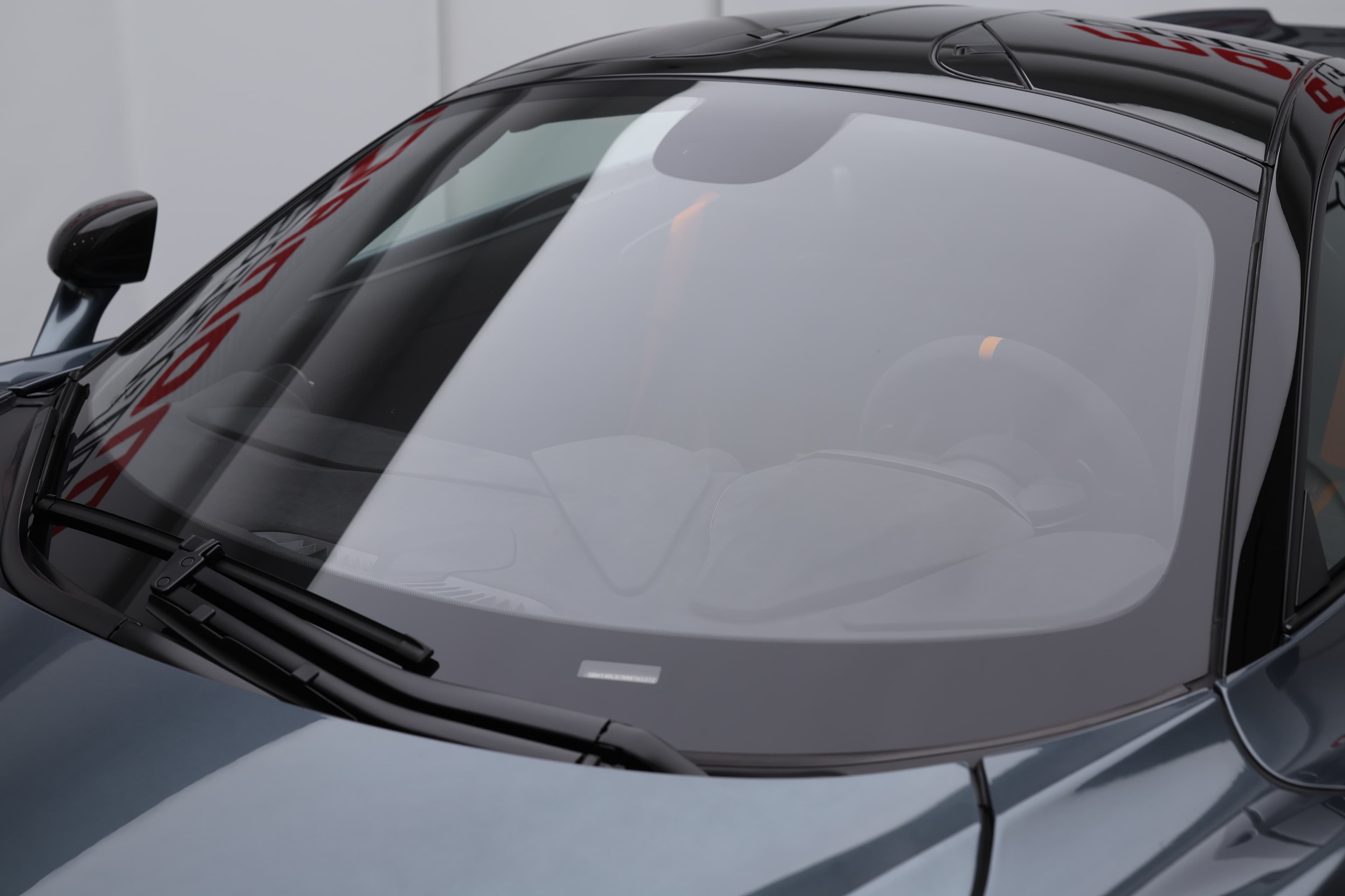 L'image montre le pare-brise d'une McLaren 765LT, mettant en avant sa courbure élégante et son intégration fluide dans le design global de la voiture, tout en offrant une vue dégagée et une expérience de conduite immersive.