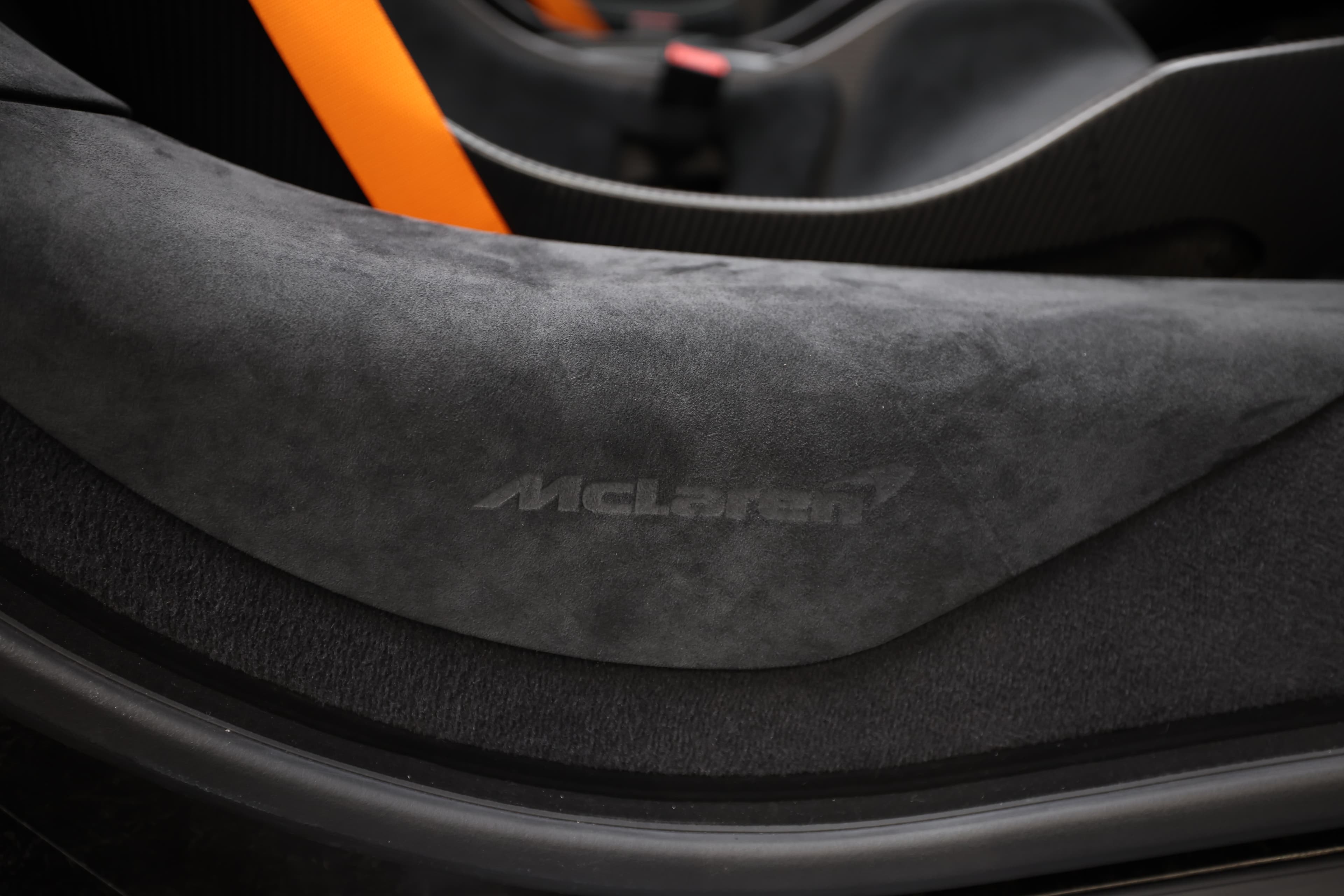 L'image met en avant le logo McLaren sur un revêtement en alcantara à l'intérieur d'un véhicule, soulignant l'élégance et le luxe des matériaux utilisés, tout en reflétant l'identité de la marque dans un environnement haut de gamme.