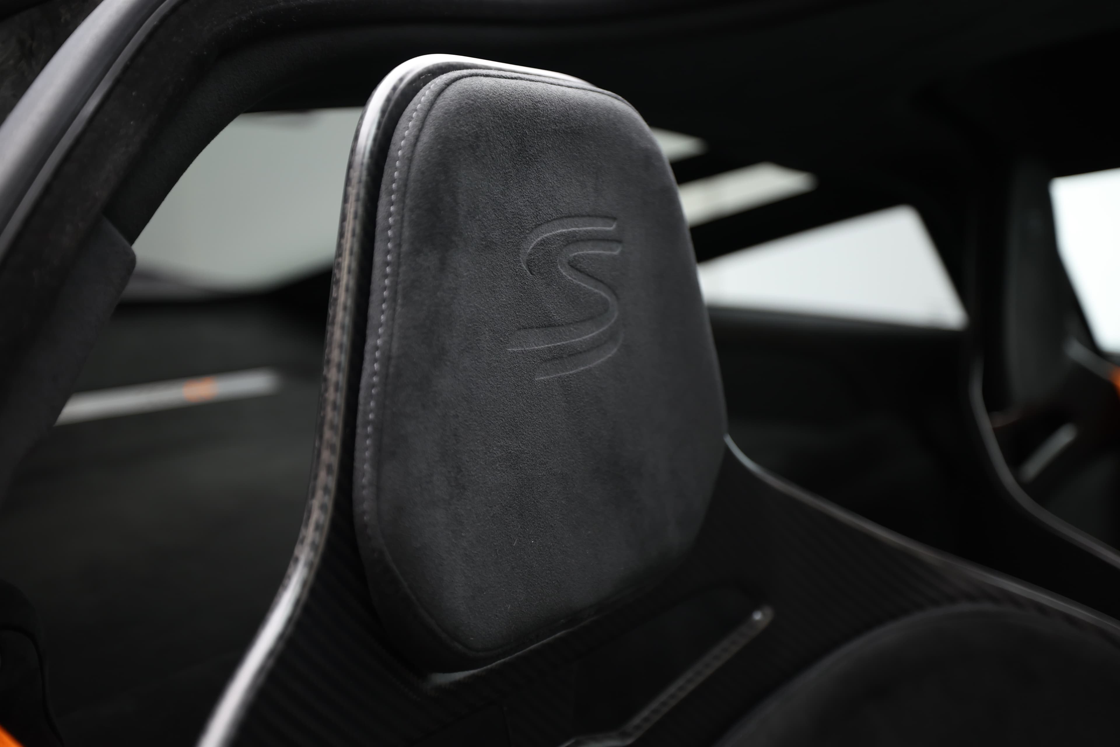 L'image se concentre sur l'appui-tête du siège de la McLaren, mettant en évidence son design sculpté et sportif, ainsi que les matériaux de haute qualité utilisés, qui reflètent l'orientation vers la performance et le confort de cette supercar.