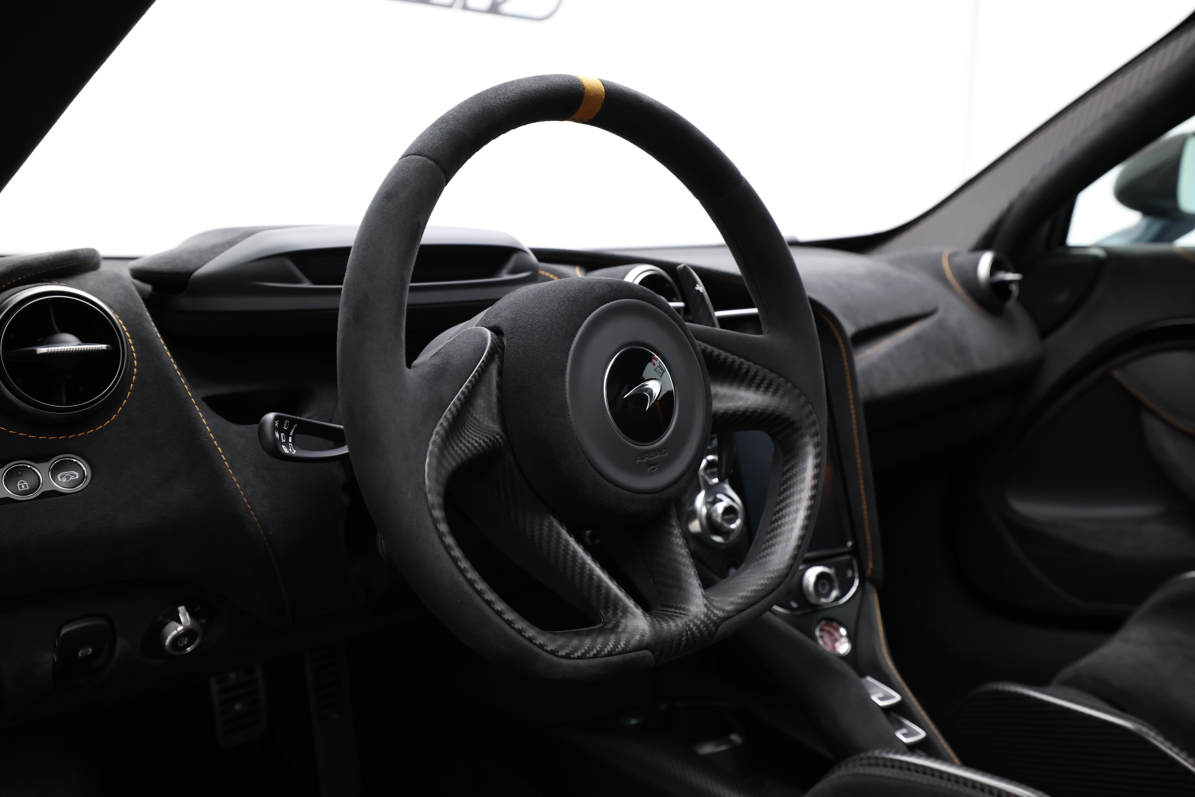 L'image présente un volant en fibre de carbone, mettant en avant son design léger et sportif. Ce matériau offre une excellente prise en main et une esthétique haut de gamme, typique des voitures de performance. Les détails de finition et les commandes intégrées ajoutent à la fonctionnalité et au style du volant.