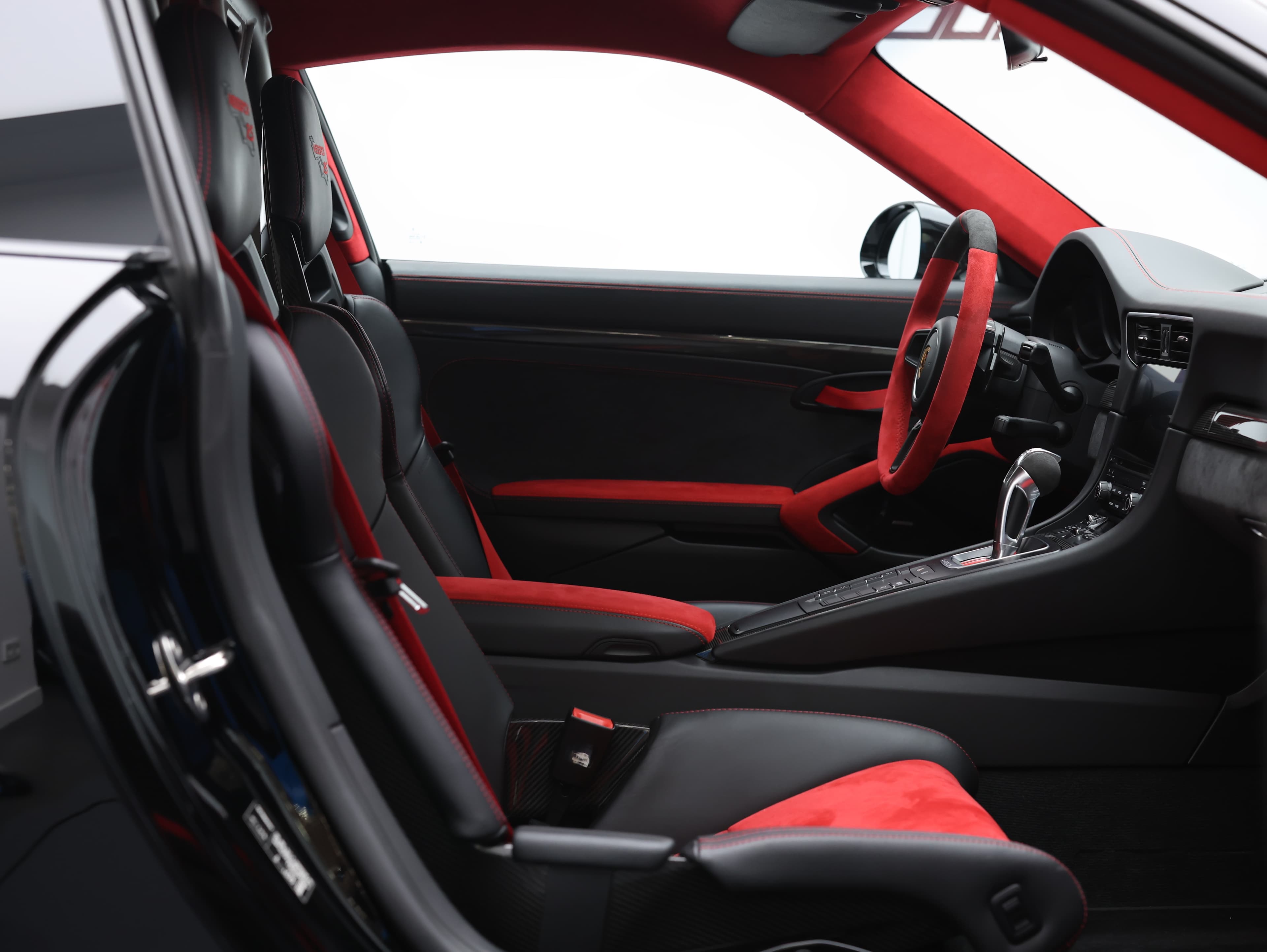 Photo de l'intérieur de la Porsche 911 GT2 RS, combinant cuir noir et Alcantara rouge, créant une ambiance sportive et luxueuse qui souligne le caractère haut de gamme de ce modèle.