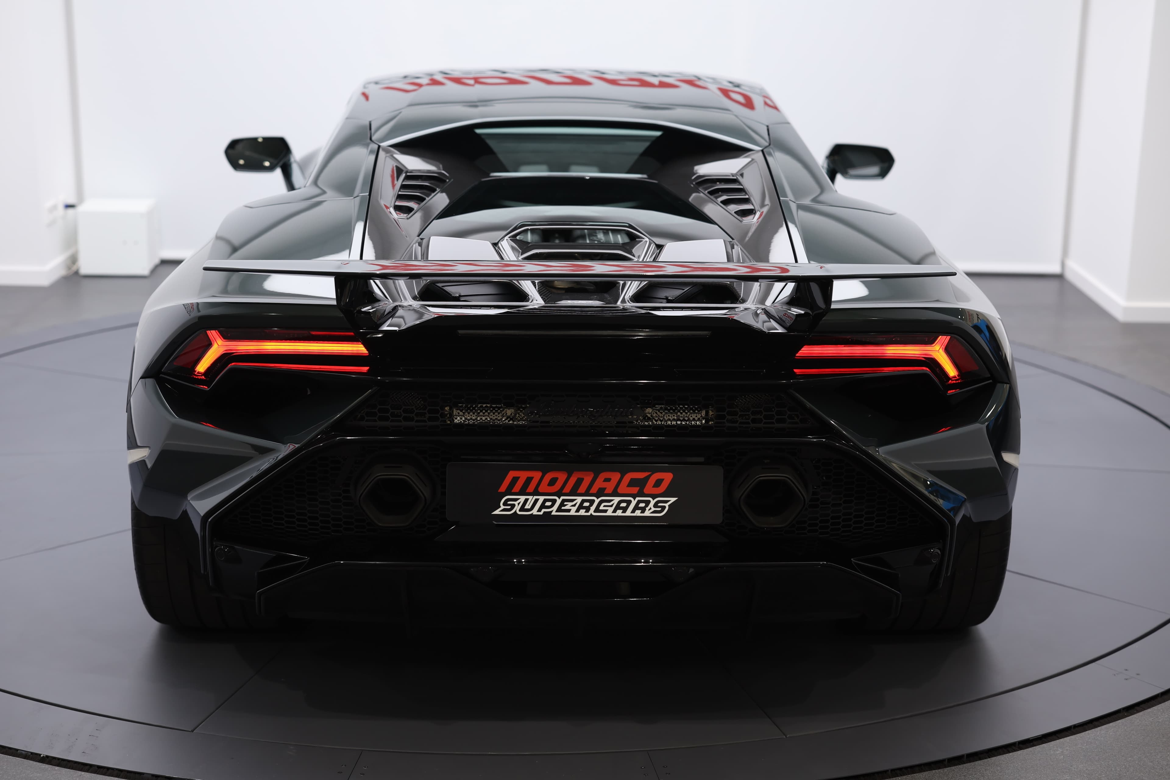 L'arrière de la Lamborghini Huracán Tecnica, avec les feux allumés, présente une silhouette audacieuse et captivante, mettant en valeur le design distinctif des feux et l'agressivité globale de la voiture.