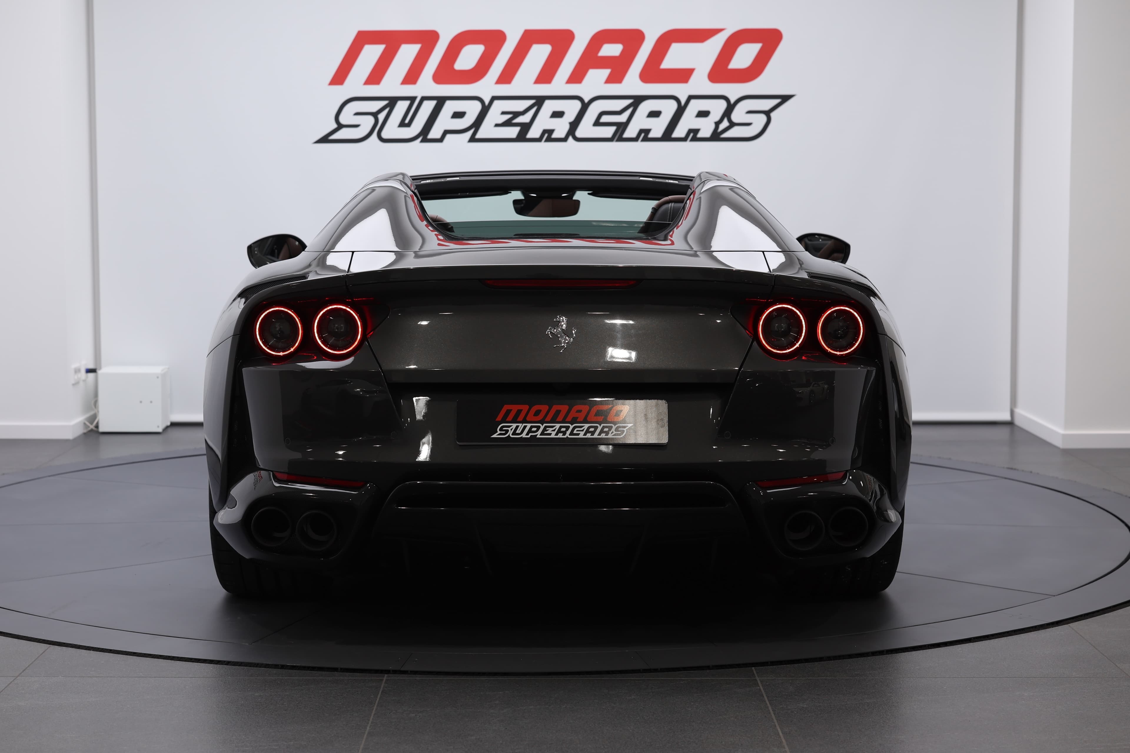 La photo capture la Ferrari 812 GTS de derrière, avec les feux arrière allumés, soulignant son design audacieux et sa présence saisissante sur la route.