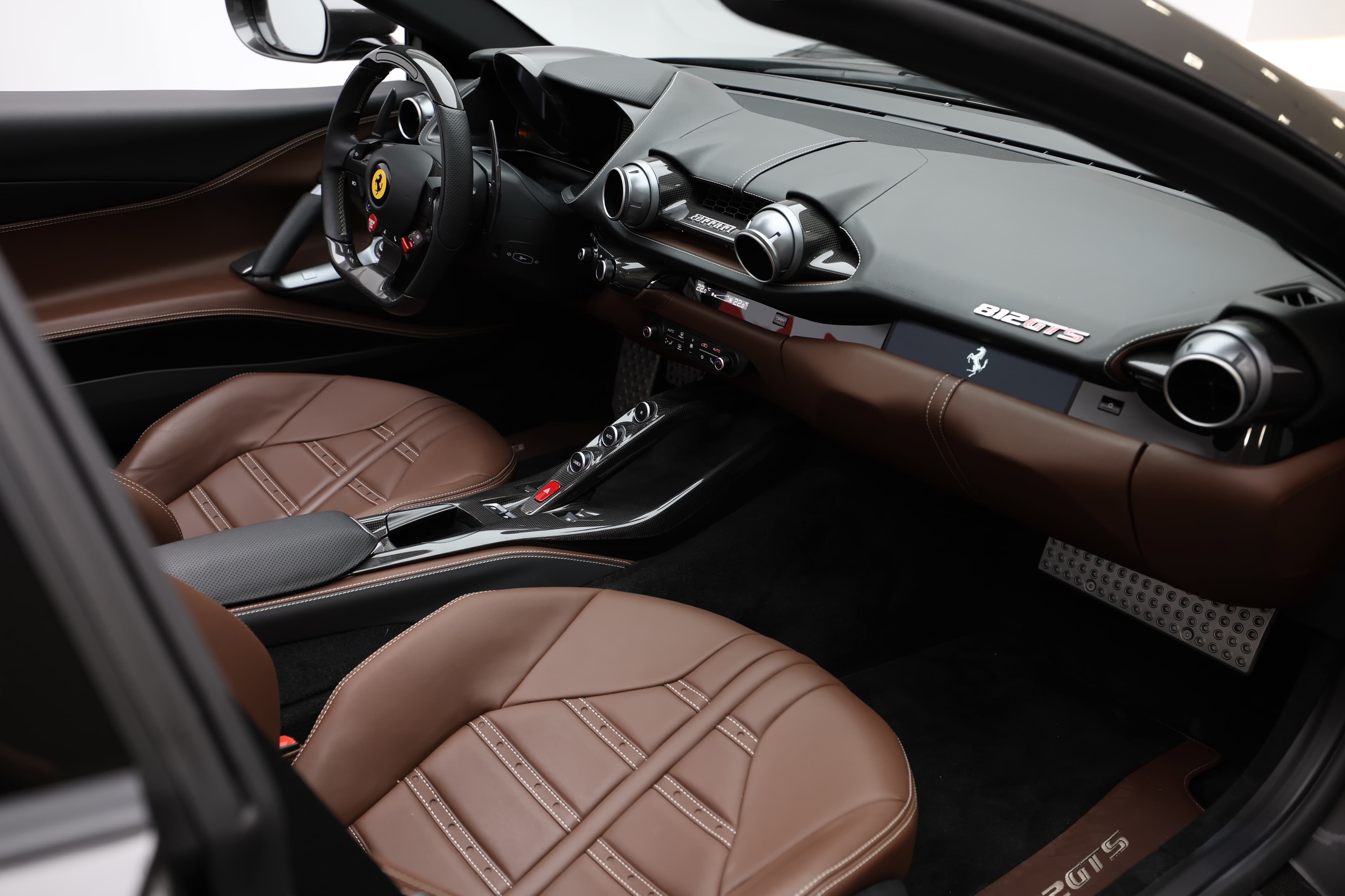 Découvrez l'intérieur spacieux de la Ferrari 812 GTS, où chaque détail est soigneusement conçu. Les sièges en cuir chocolat, combinés à des éléments en carbone, créent une ambiance luxueuse et sportive. Le tableau de bord ergonomique et les commandes intuitives renforcent l'expérience de conduite, alliant confort et performance.