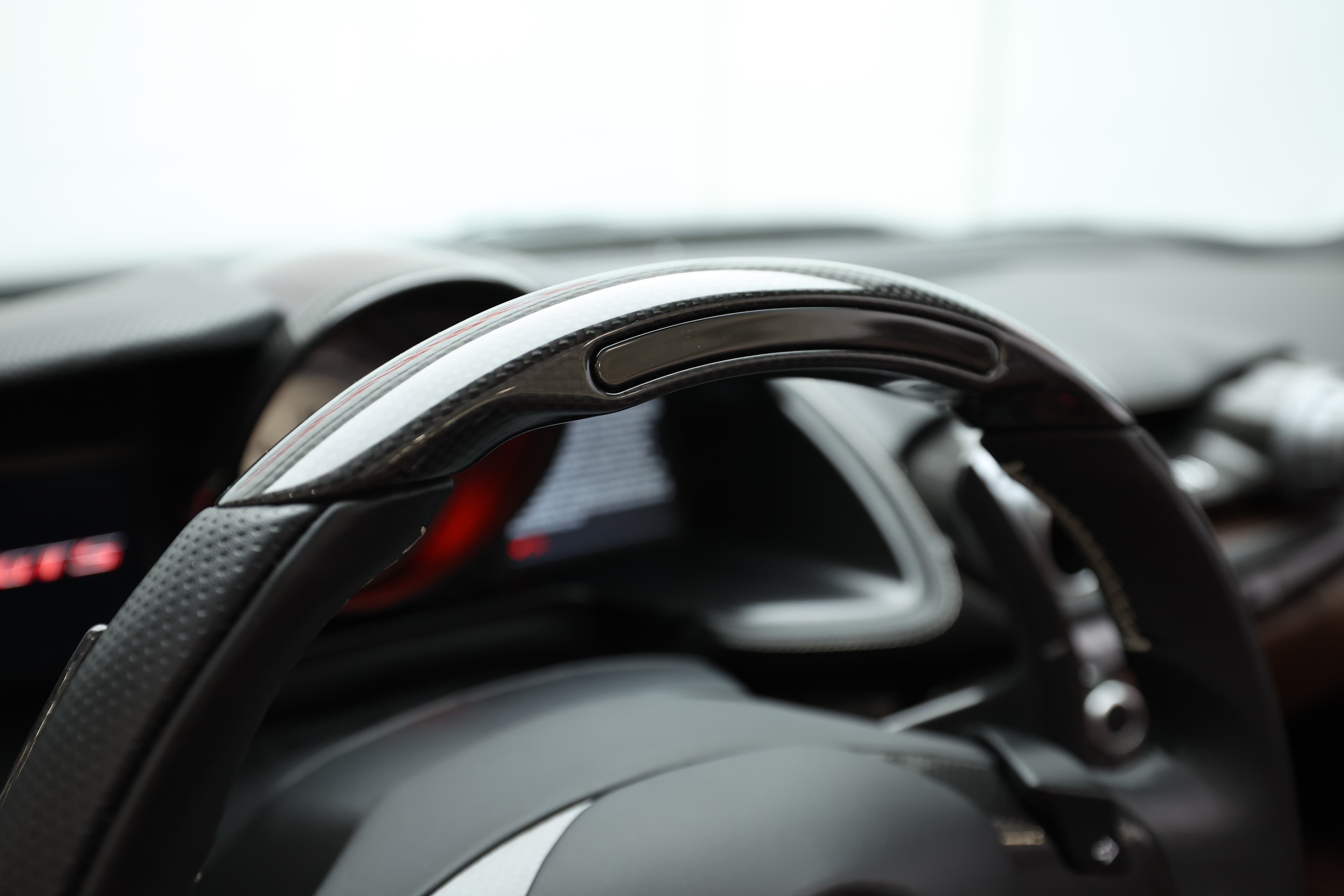 Voici un détail du volant de la Ferrari 812 GTS, mettant en avant la finition et le design ergonomique. La texture et les commandes intégrées garantissent une prise en main optimale, essentielle pour une conduite sportive.