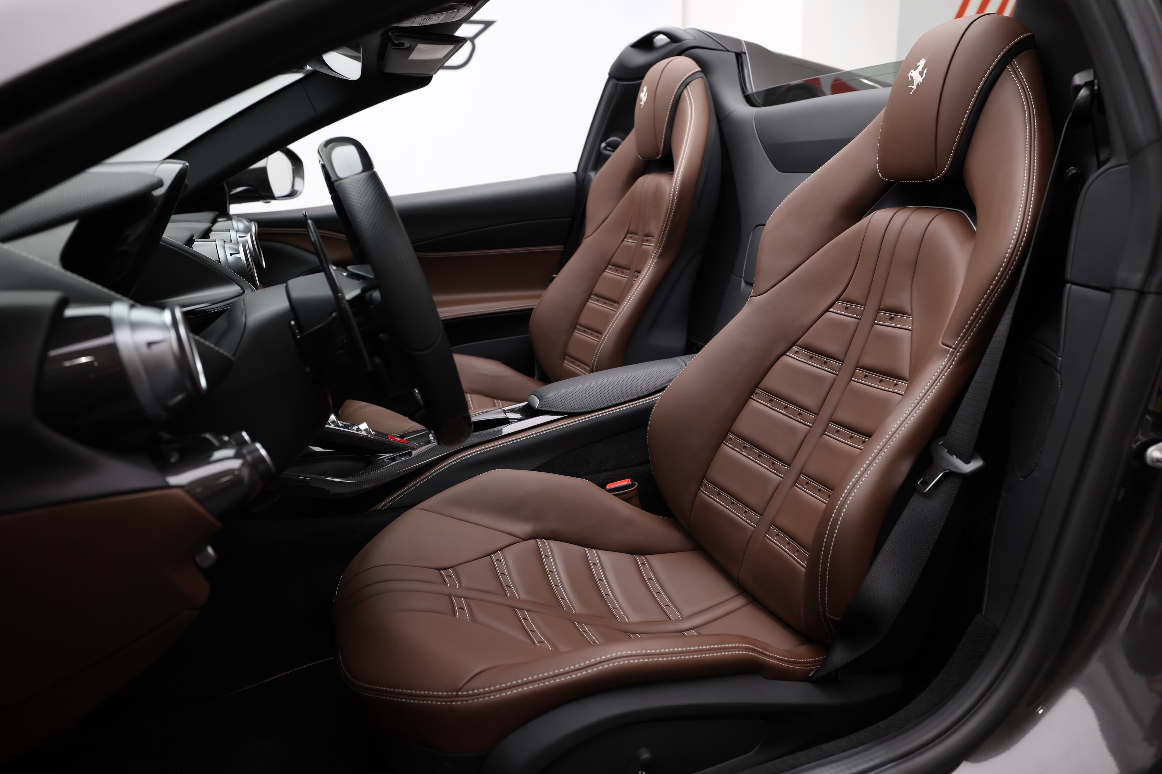 Voici une vue d'ensemble des sièges avant de la Ferrari 812 GTS, mettant en valeur leur design sportif et leur confort. Le cuir de haute qualité et les motifs de couture ajoutent une touche d'élégance, tout en offrant un excellent soutien pour une conduite dynamique.