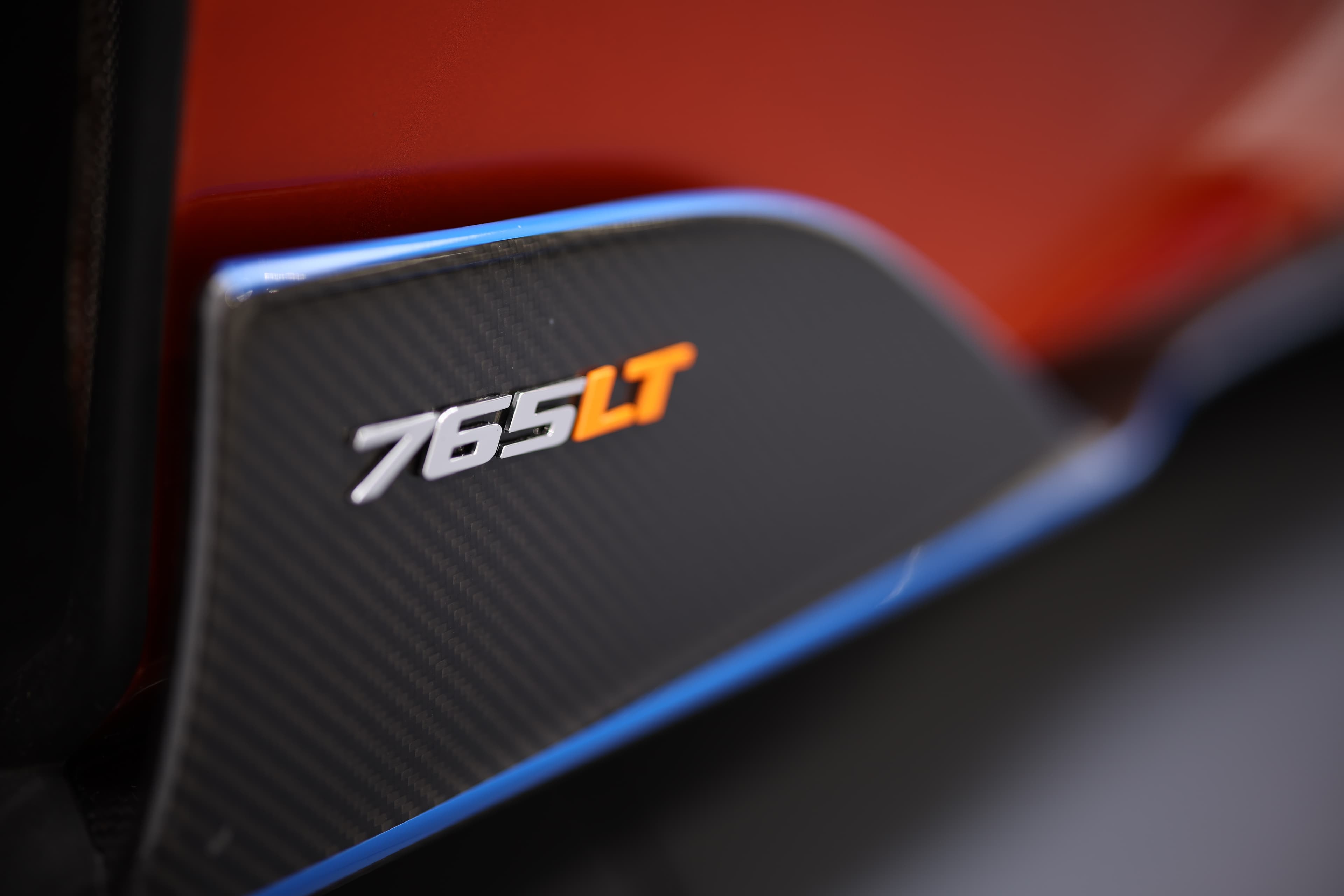 Gros plan sur le '765LT' de la McLaren, mettant en avant le matériau en carbone et les détails raffinés, soulignant l'identité et la performance de ce modèle emblématique.