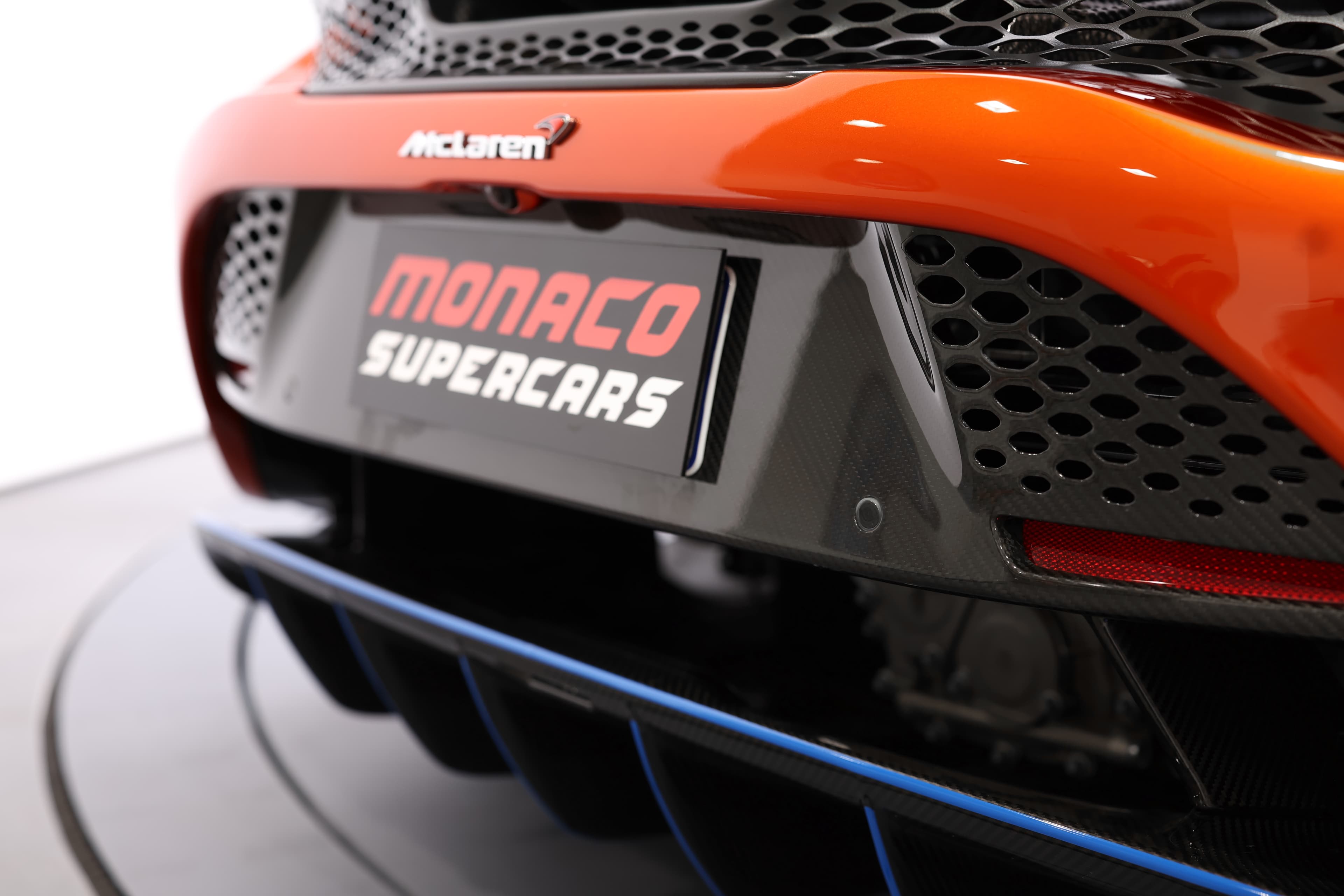 Gros plan sur le badge de la McLaren 765LT, mettant en avant le logo et le design du diffuseur arrière, soulignant l'identité de la marque et l'importance du style dans le monde des supercars.