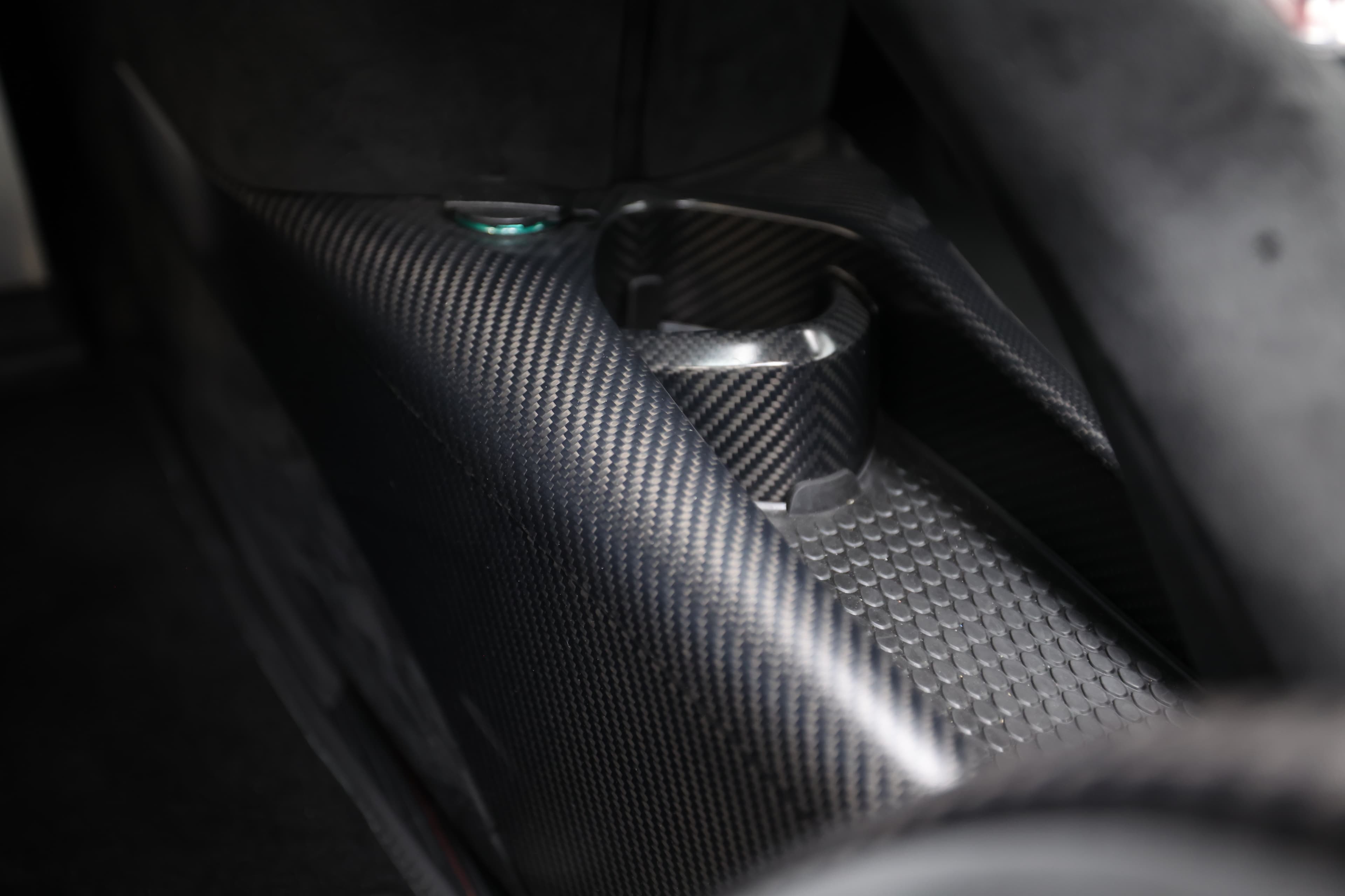 Gros plan sur le détail en carbone de l'intérieur de la McLaren 765LT, mettant en avant les textures et la finition haut de gamme, illustrant l'engagement envers la légèreté et la performance.