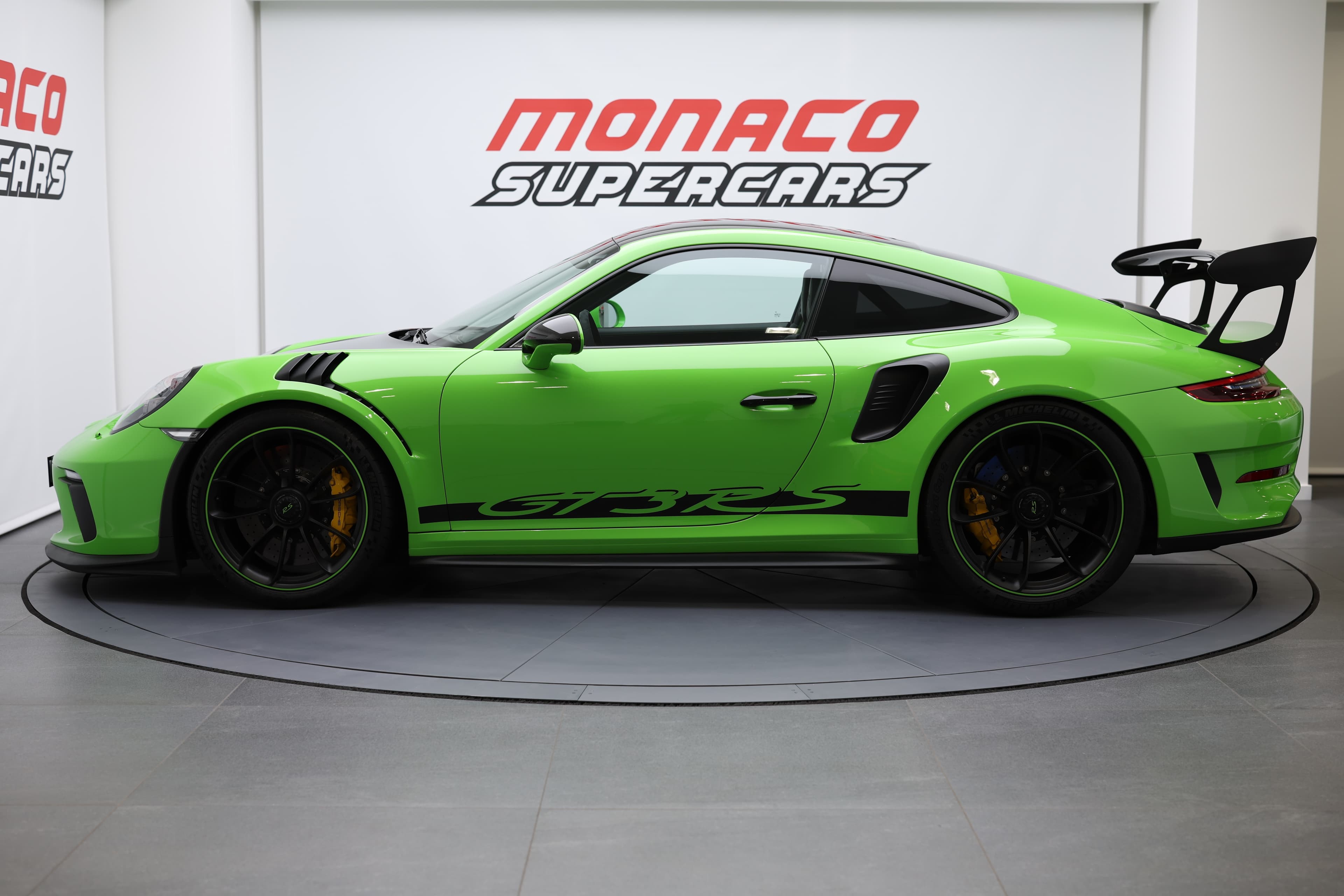 Vue de profil d’une voiture de sport verte exposée chez Monaco Supercars, mettant en avant sa silhouette racée et son design ultra-performant.