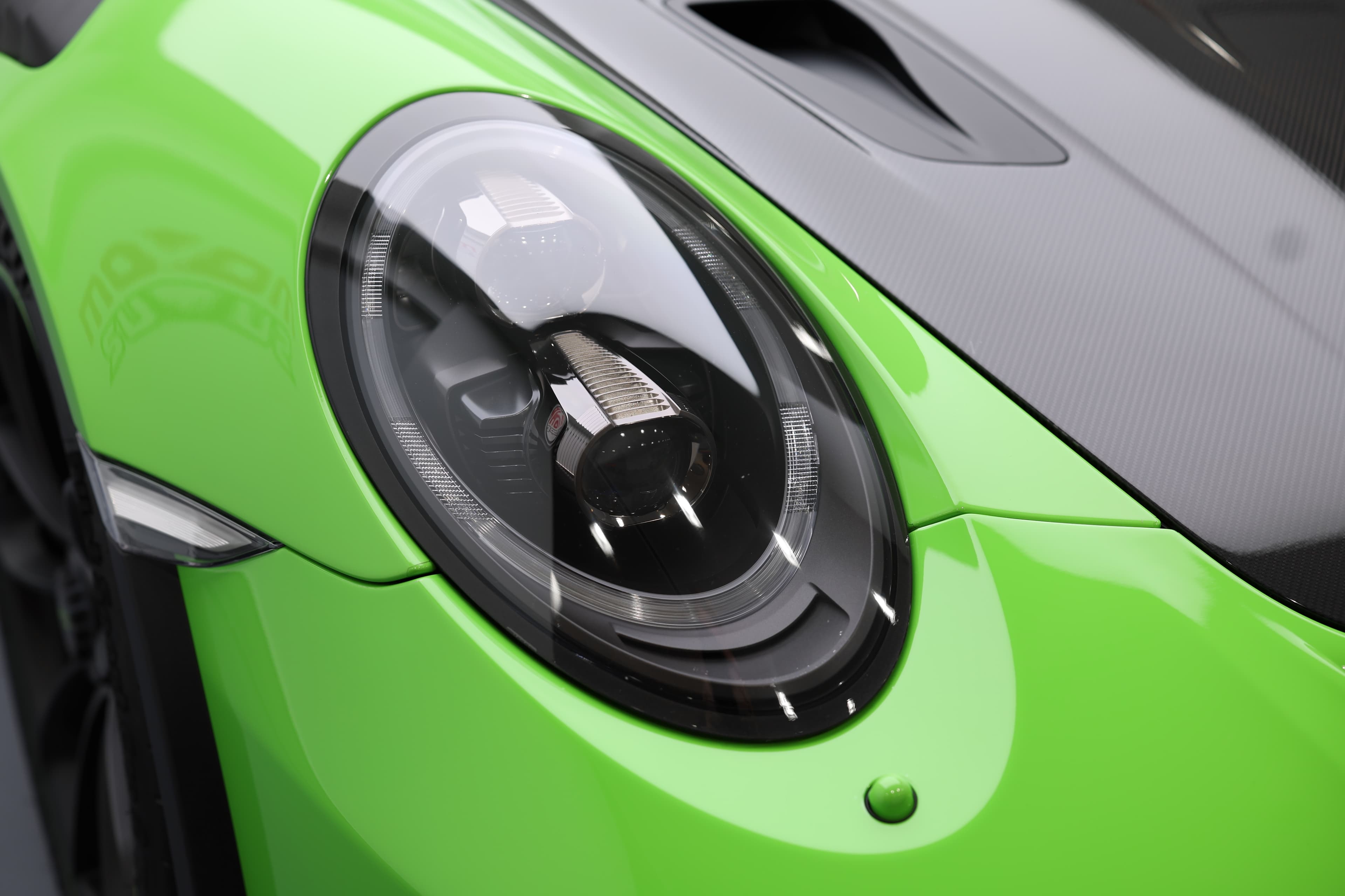 Détail du phare avant emblématique de la Porsche 911 GT3 RS 991 verte, soulignant son identité sportive et son design iconique immédiatement reconnaissable.