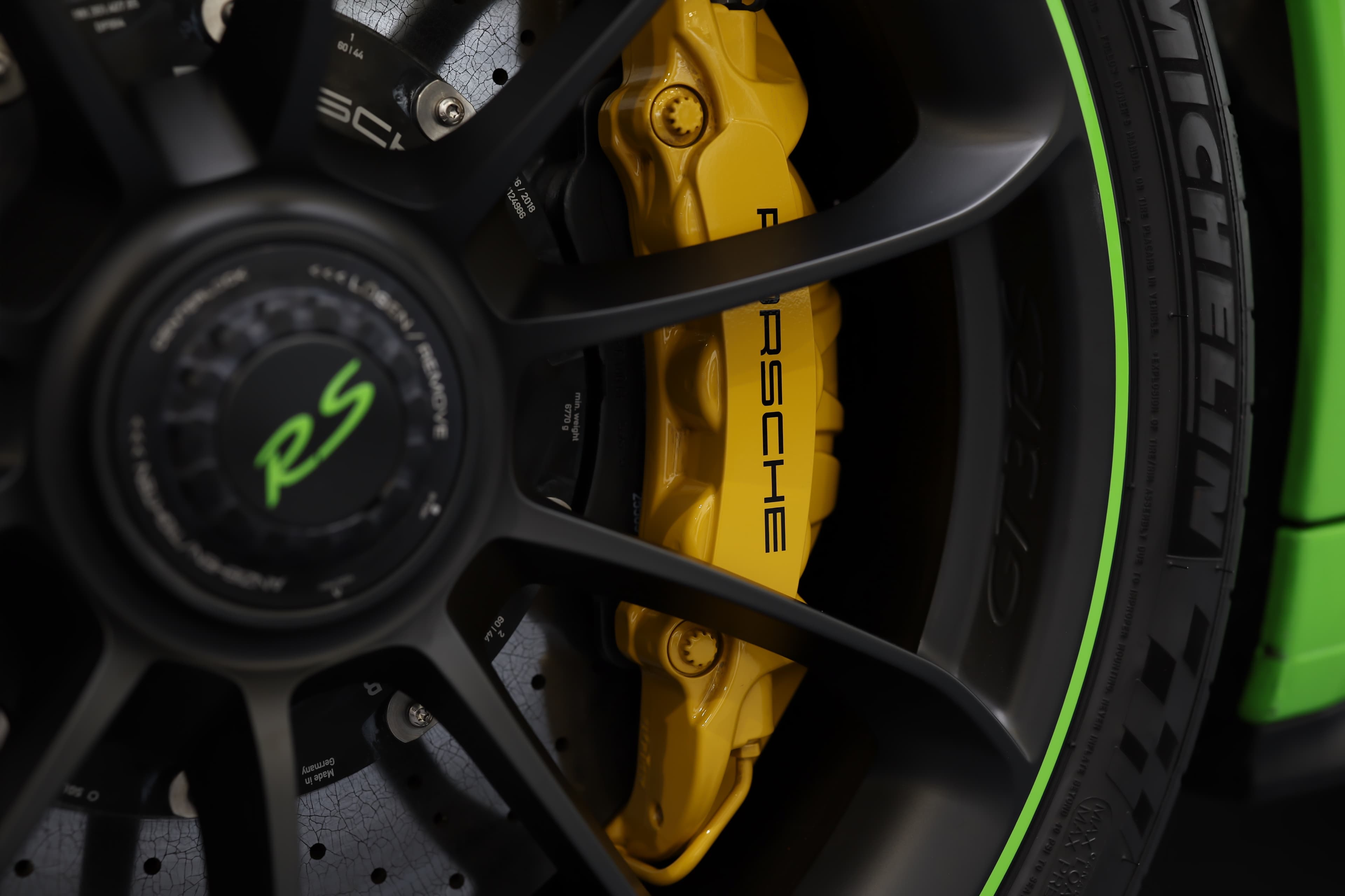 Détail du système de freinage de la Porsche 911 GT3 RS 991 verte avec freins carbone-céramique et étrier Porsche jaune, garantissant un freinage ultra-performant sur route et sur circuit.