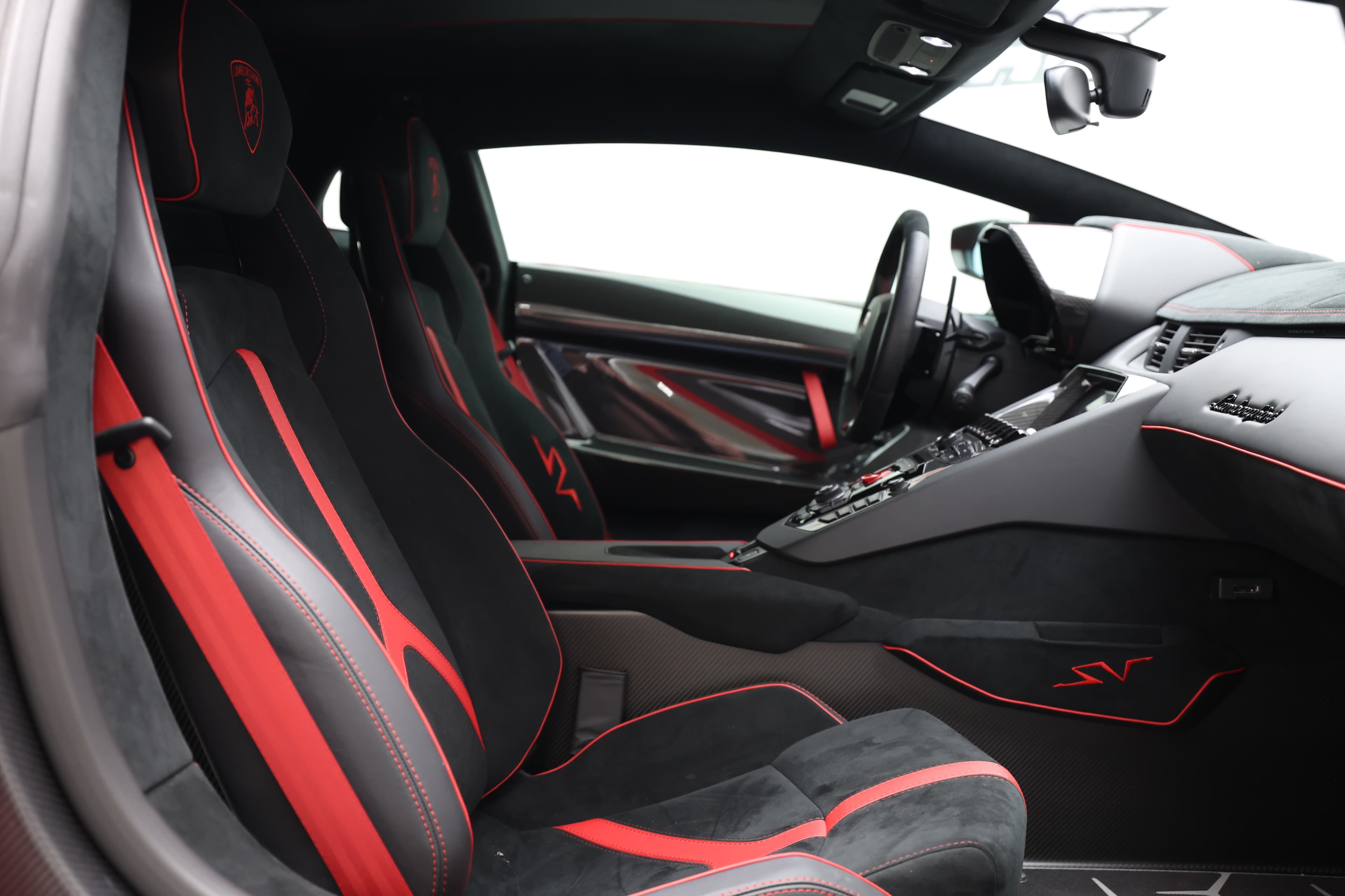 Intérieur de Lamborghini avec sièges sportifs en cuir rouge et noir, alliant luxe et performance.