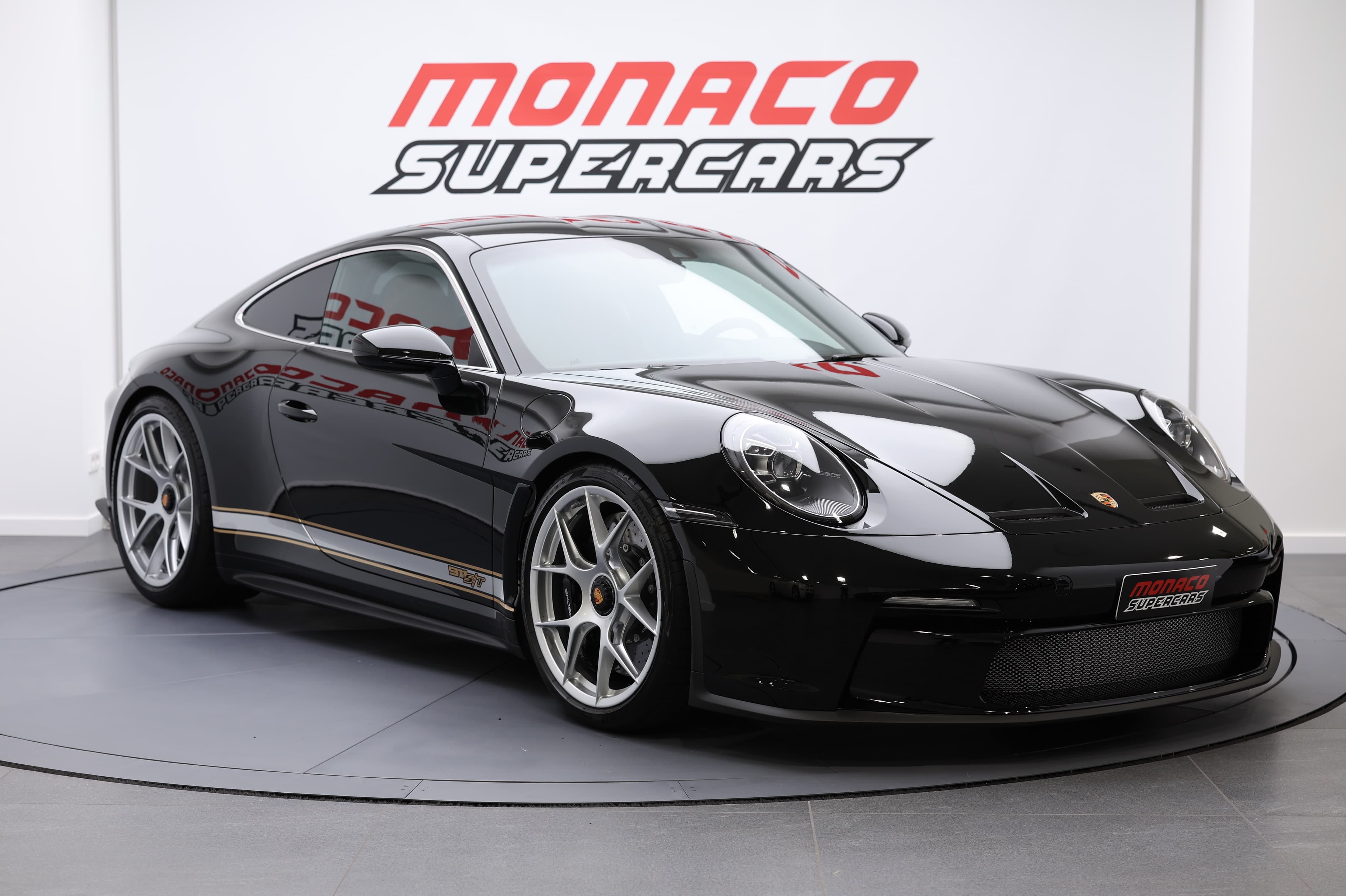 Porsche 911 en noir, vue trois-quarts avant, mettant en avant son design emblématique et ses finitions de qualité, exposée à Monaco Supercars, un véritable symbole de performance et d'élégance.