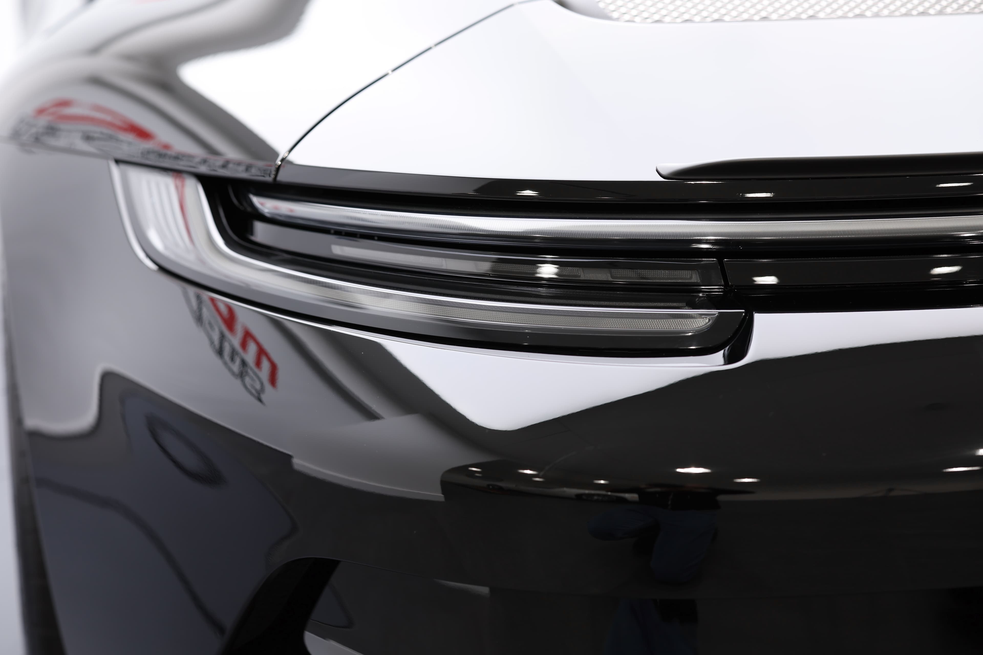 Détail sur les feux arrière de la Porsche 911, soulignant le design aérodynamique et futuriste. Les lignes fluides et la finition élégante ajoutent à l'esthétique générale du véhicule, tout en renforçant sa présence sur la route. Ce design témoigne de l'engagement de Porsche envers l'innovation et la performance.