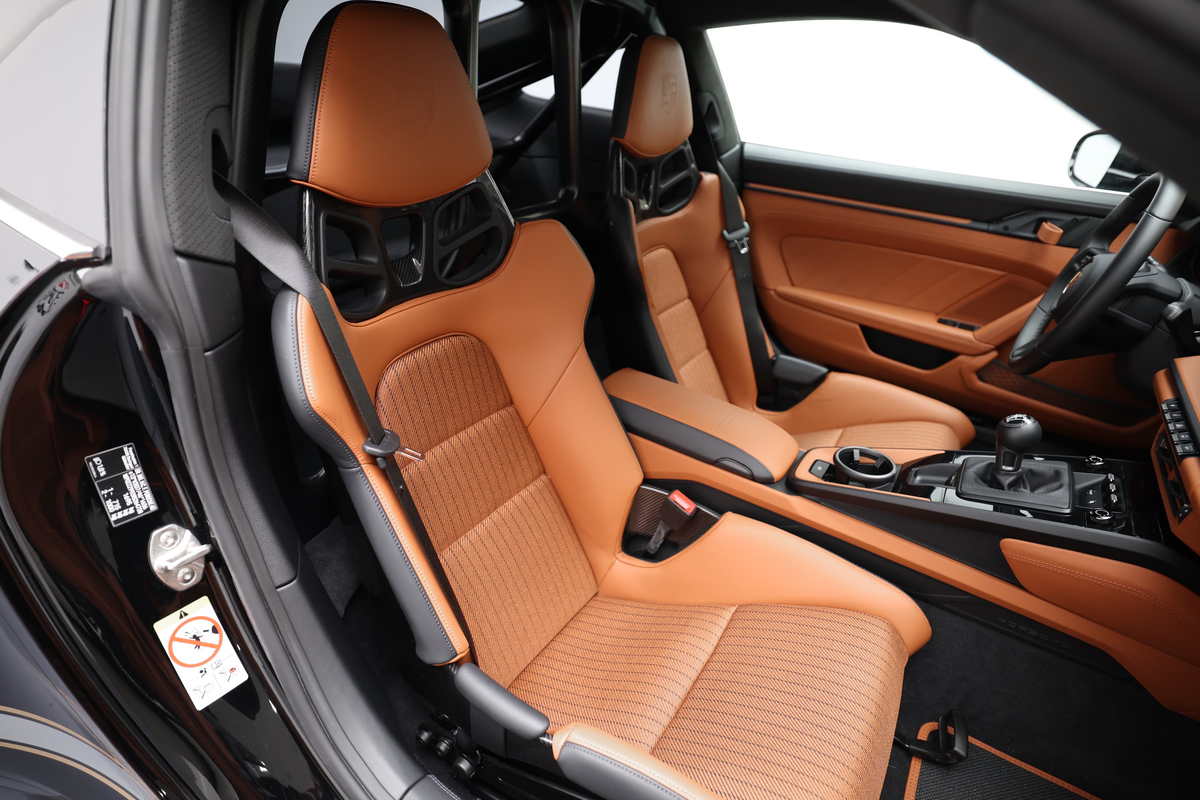 Détail de l'intérieur, mettant en avant les sièges en cuir orange et le tableau de bord sportif.